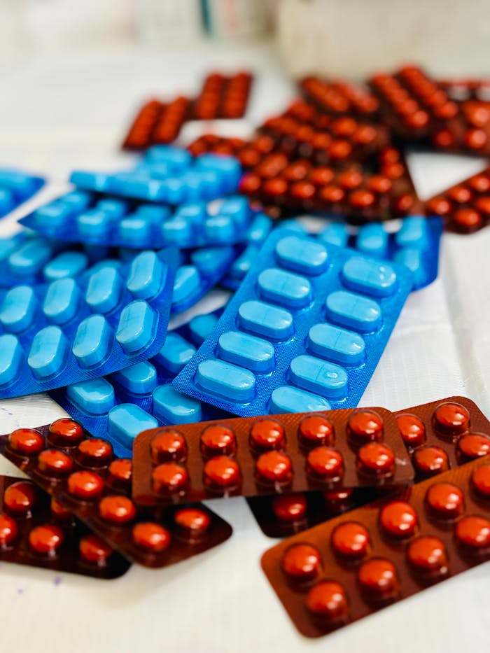 Various blue and red pills in blister packs on a white surface.